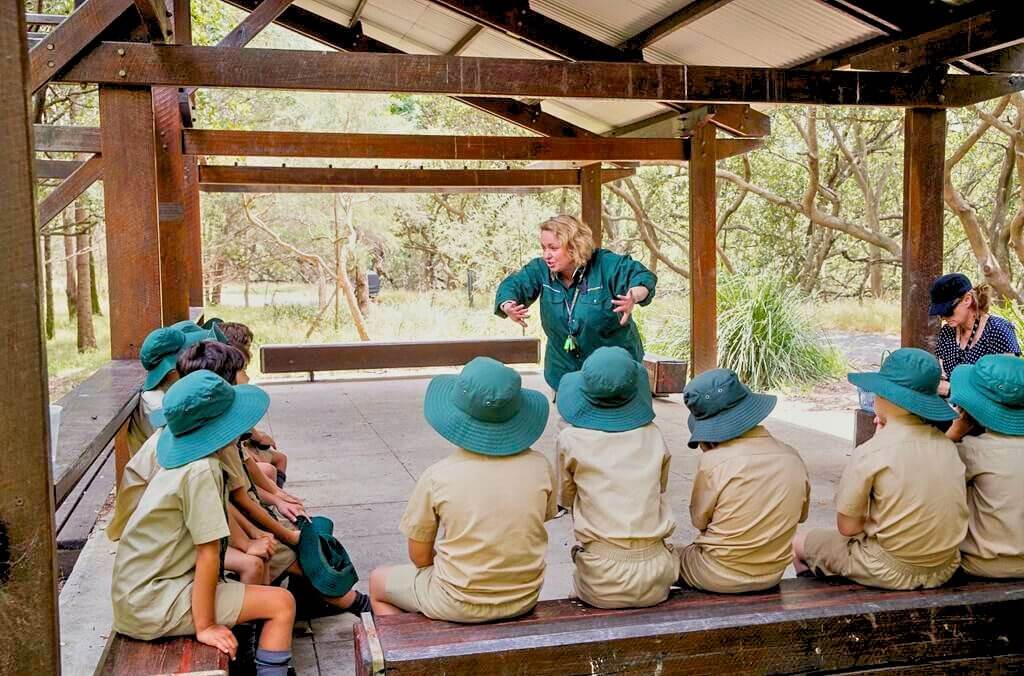 Image of students sitting under shelter listening to an instructor