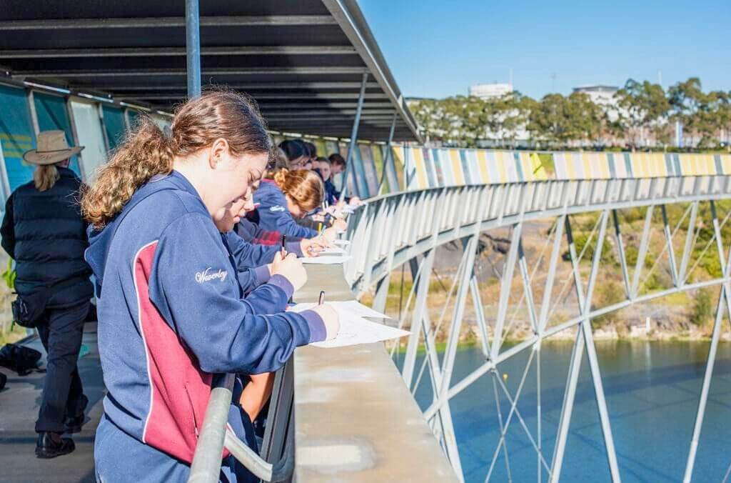 Students along a bridge filling out worksheets