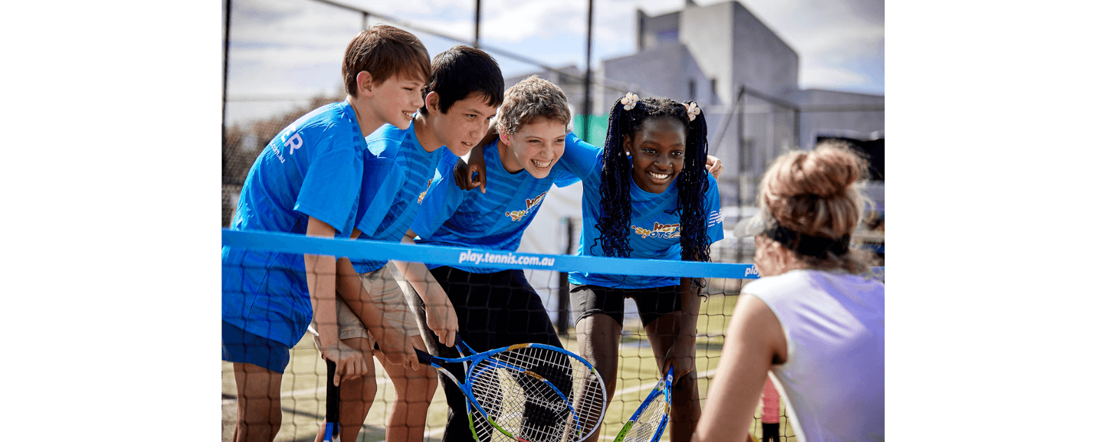 Young people and instructor with racquets on tennis court