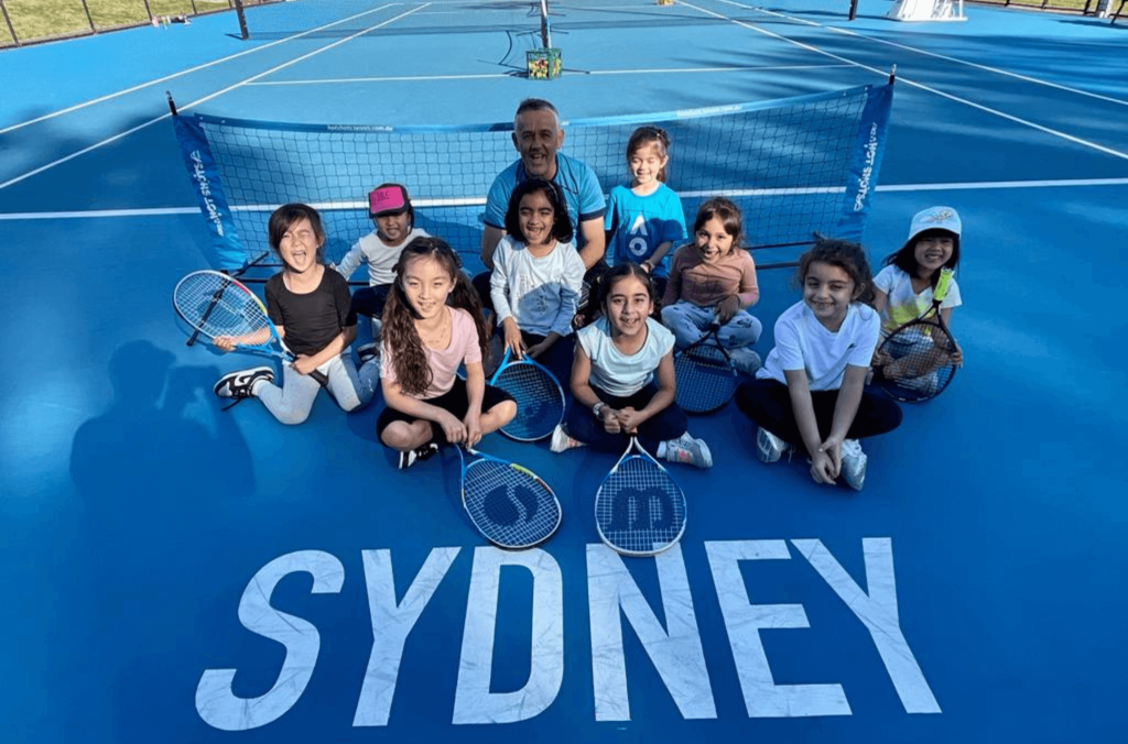 Young people and instructor with racquets sitting on tennis court